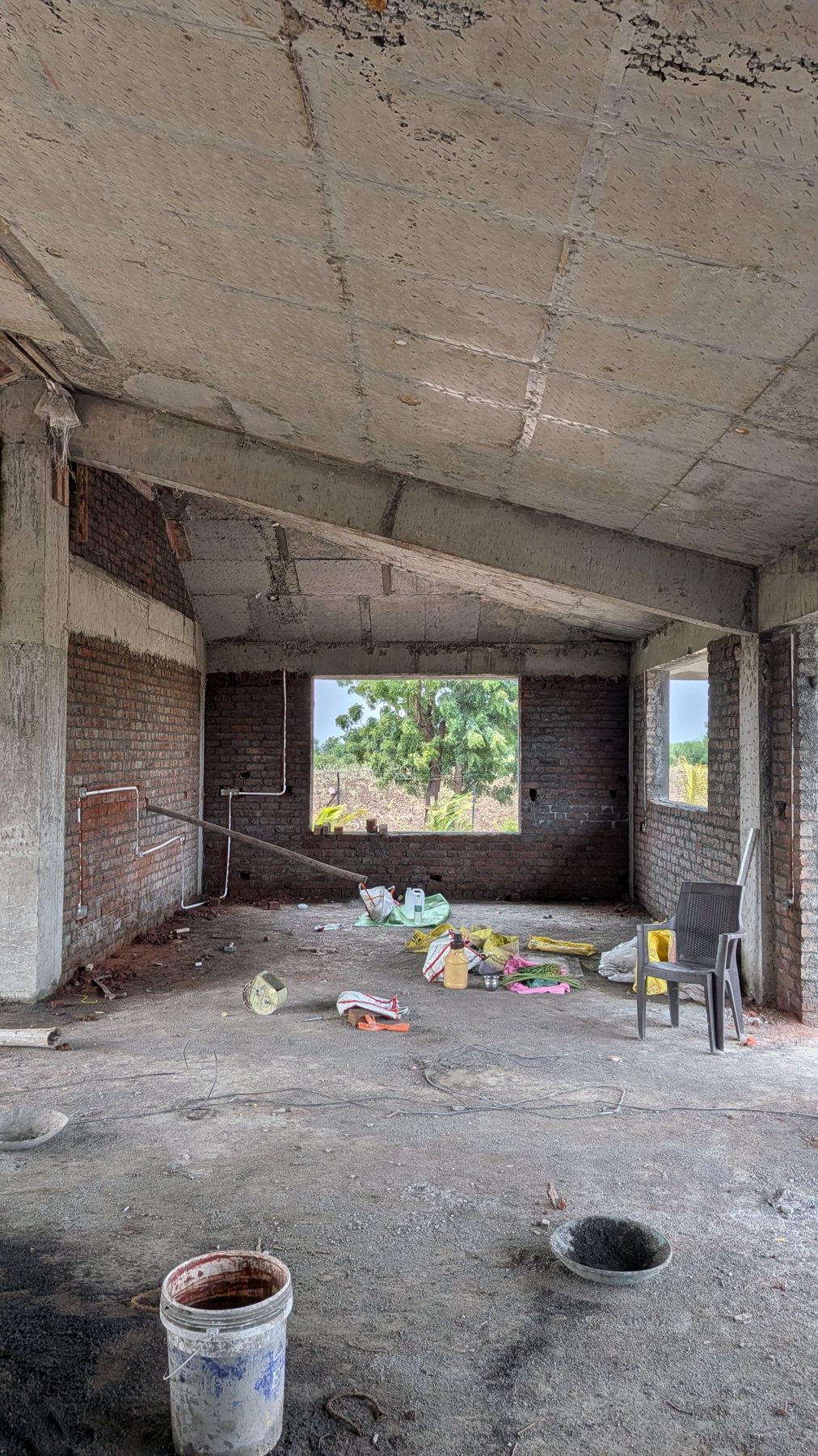 A room with exposed brick, conduits on the walls and a window to the trees, site photo