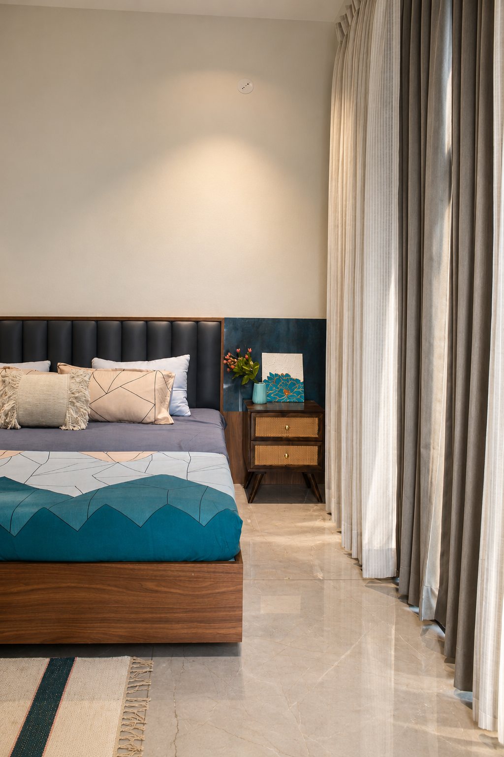 Bedroom with a teal accent panel, cane bedside table and floor-length linen curtains, photo