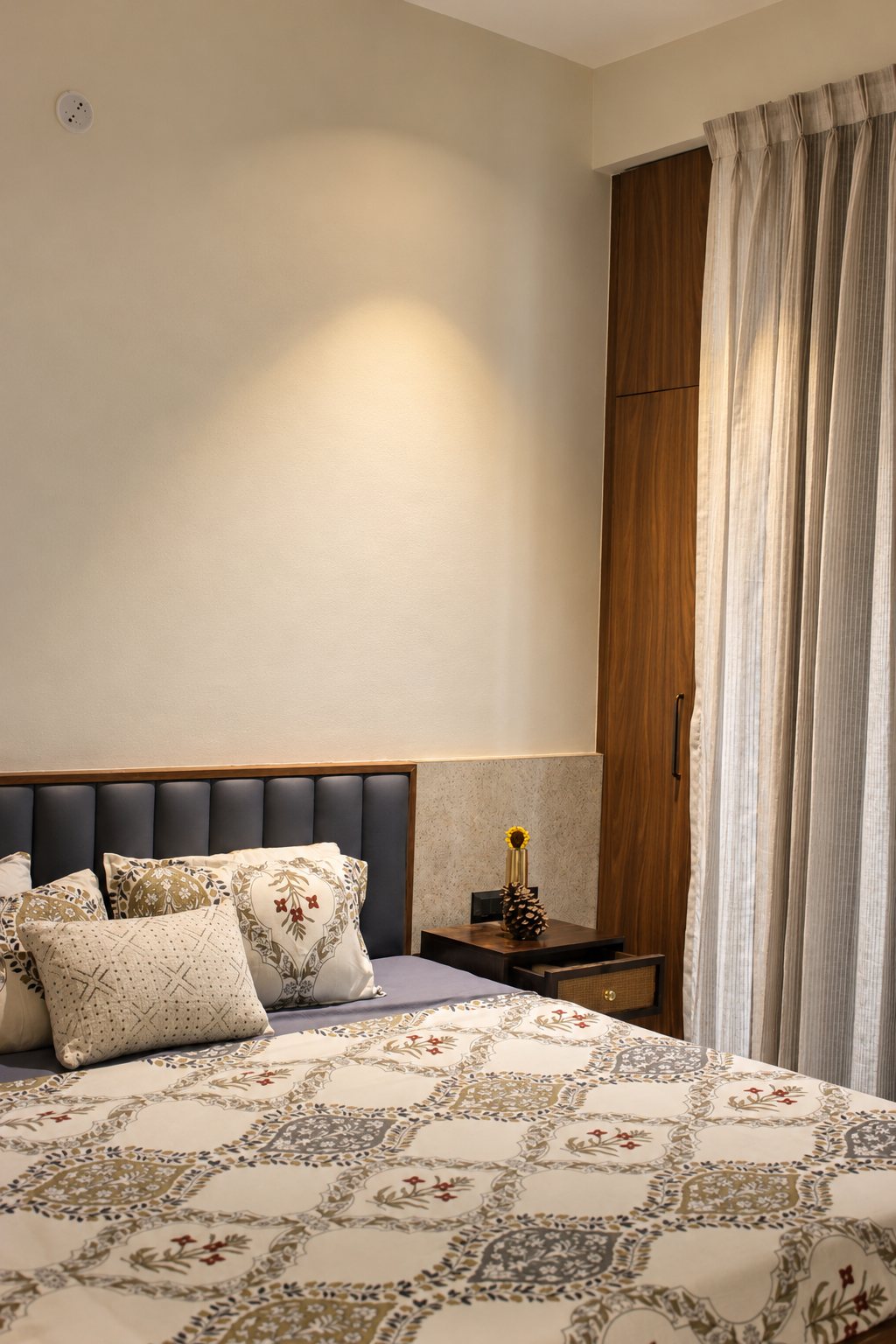 Bedroom with a textured stone panel beside the headboard and a walnut tall unit, photo